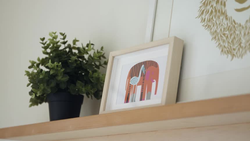Framed painting resting over the wooden shelf in a wall of a room