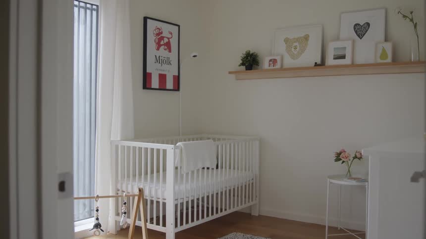 A nursery room with a white crib dresser table and shelving on the wall with art work