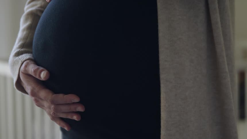 Female hand holding her pregnant belly