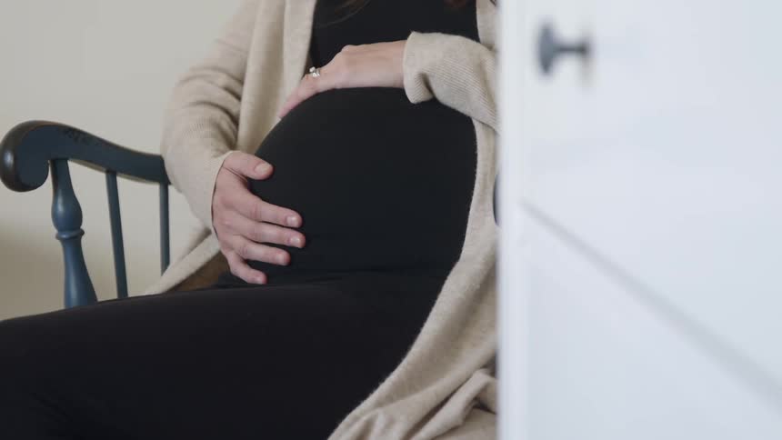 Pregnant woman holding her belly as she rocks on a rocking chair