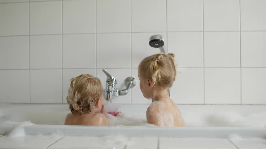 Two kids playing in a bathtub full of bubbles