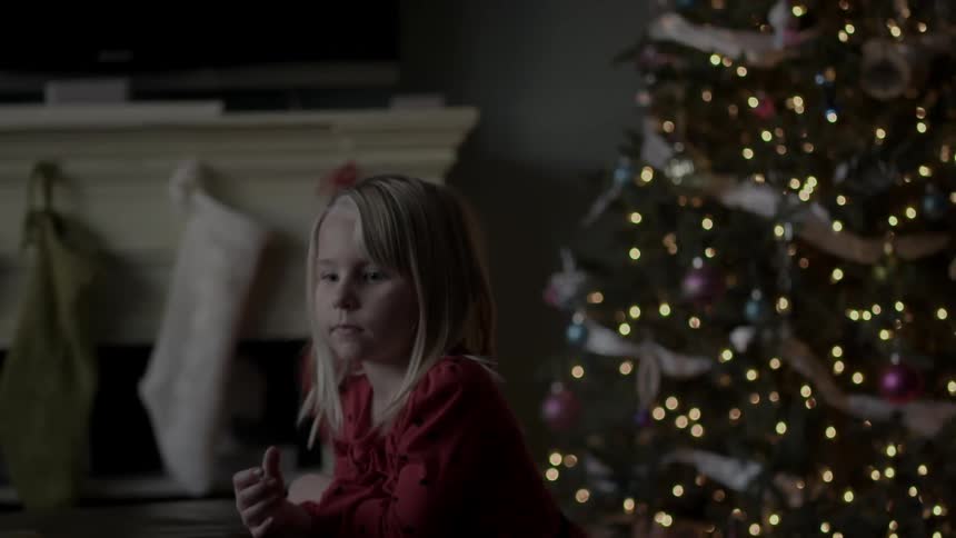 A child is sitting near a christmas tree