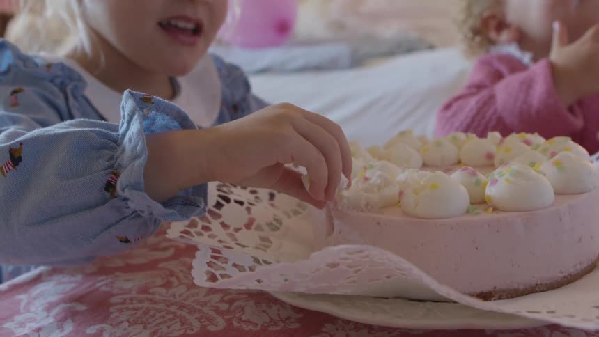 Little girl sitting in a childrens room during the day eating the frosting off of a cake