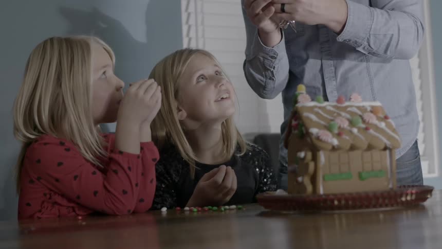 Two girls watch a man squeeze an object