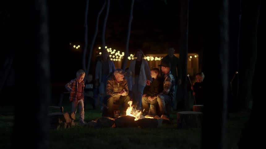 Family sitting around a campfire in the backyard at night