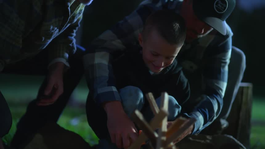 Young boy learning how to start a campfire using flint and steel