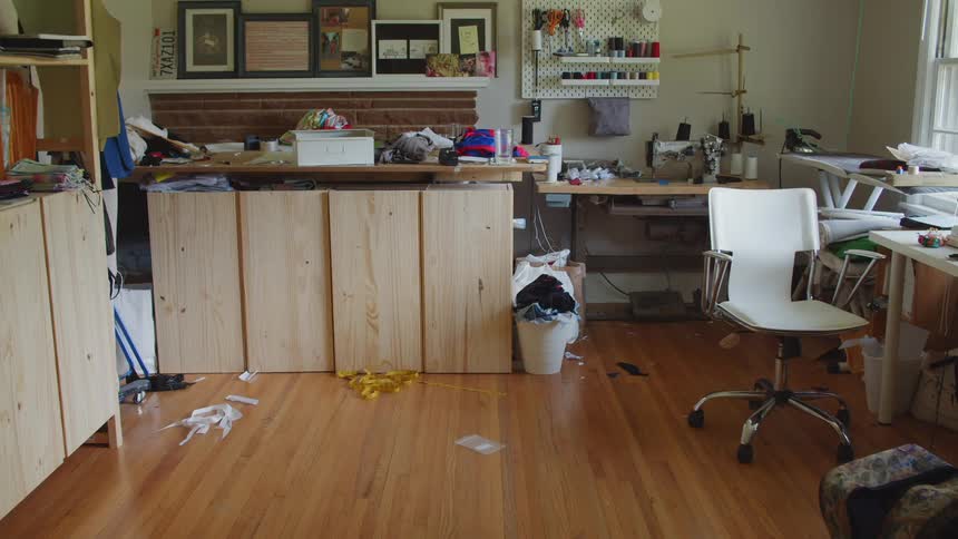A room with a chair a desk threads and a sewing machine