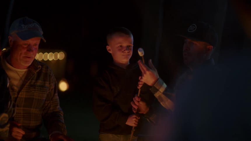 A group of people sitting around the campfire roasts marshmallows