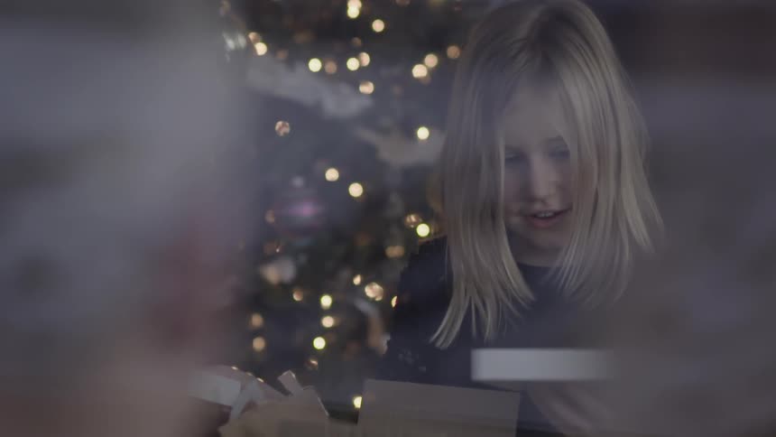 A young girl opens the container of a a gift at christmas