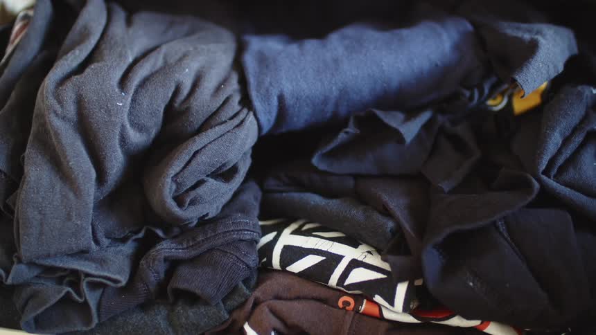 Shirts and jeans folded up into rolls stacked on top of each other