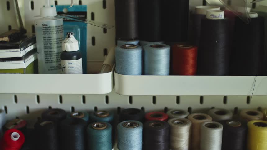 Sewing threads of multiple colors and sewing supplies on top of shelves