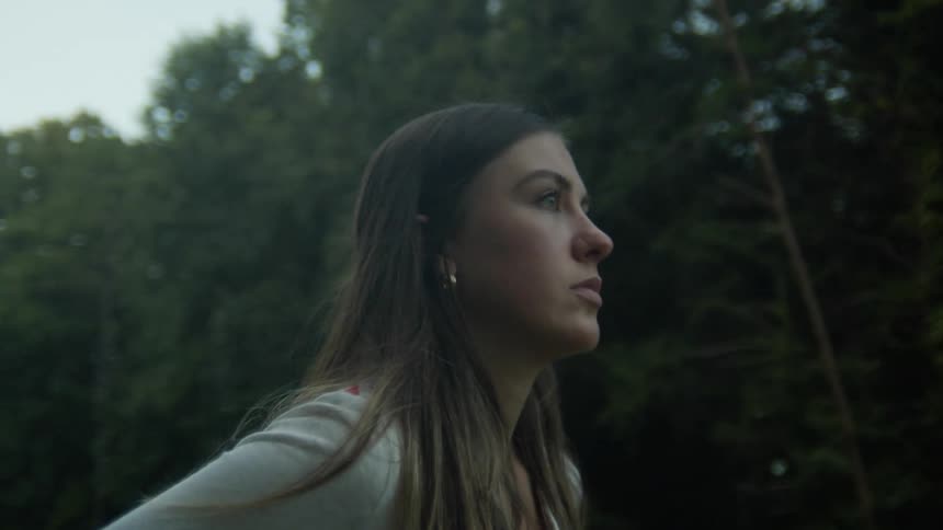 Young woman standing outdoors next to the trees and power lines looking at the horizon