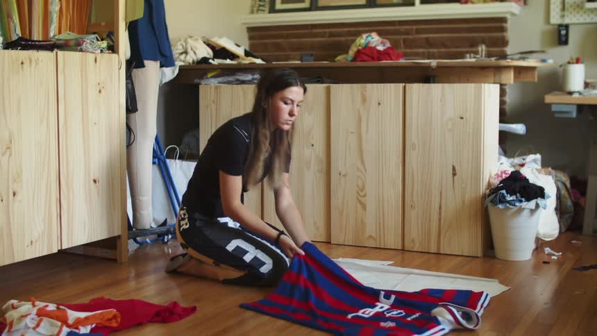 Young long haired woman sitting on the floor with clothing patterns and a tshirt