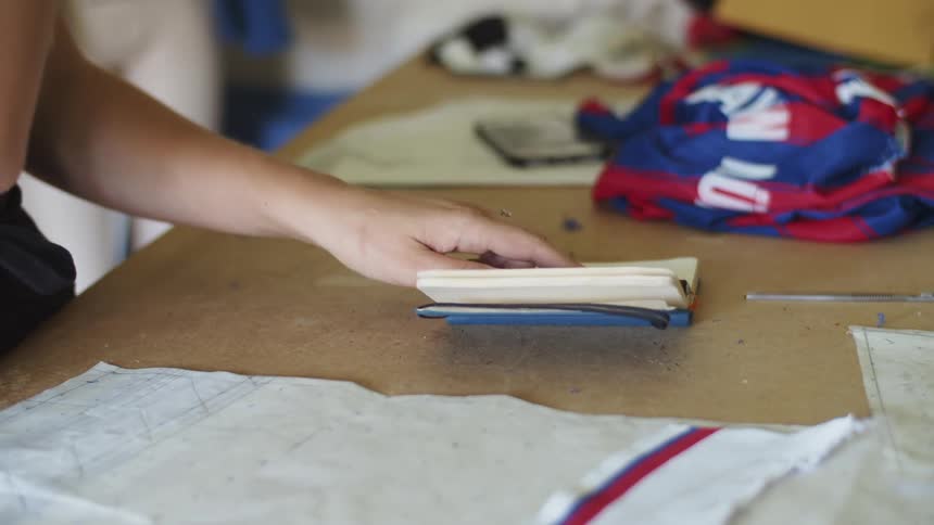 Seamstress writes in a notebook with a pen