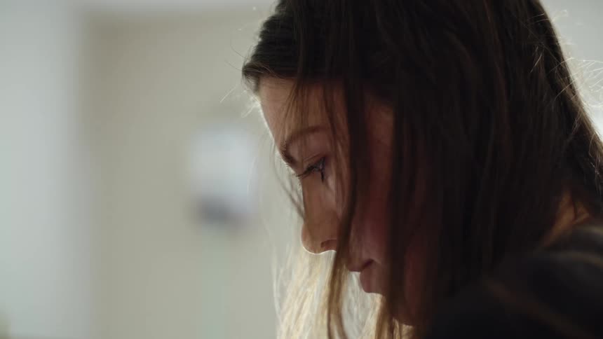 Woman with her hair in her face in a room looking down