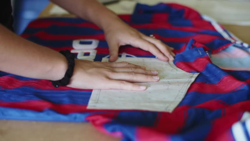 Woman placing an outline and measuring a red and blue shirt on a table