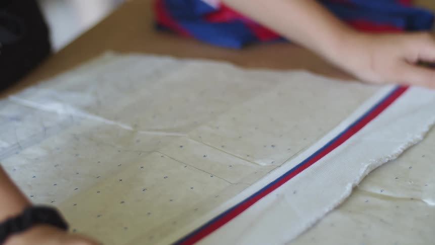 Woman measuring a piece of fabric against a reference sheet on a wooden table