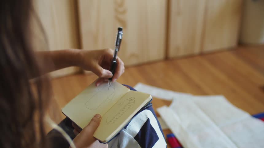 Woman taking notes on a note pad with a pen in a room at home