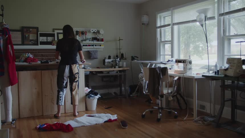A woman drapes a piece of fabric on a dress form in her sewing room at home