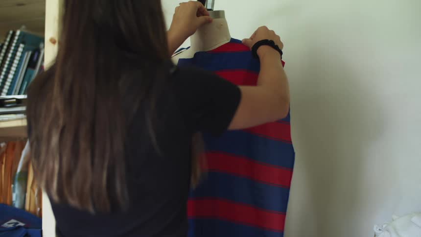 A woman is in a room and places fabric on a dress form and pins it