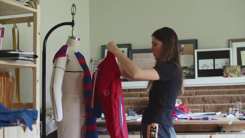 Woman measuring fabric for a shirt onto a mannequin in a home workshop