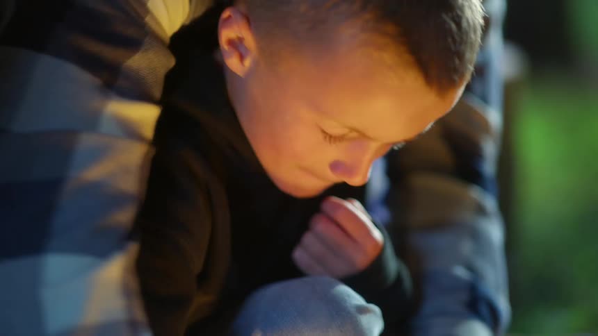Boy learning how to light a fire using flint and steel at night