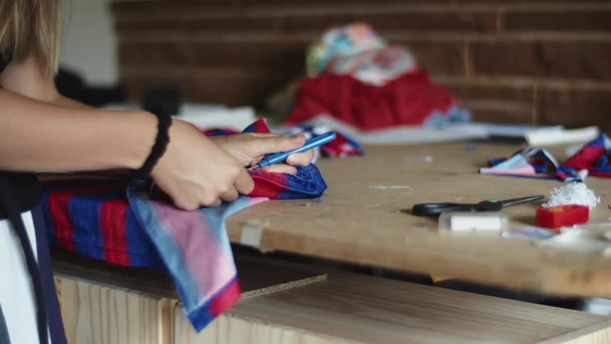 A woman stands at a table and removes a seam from a shirt