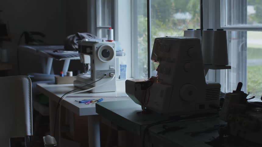 A sewing machines sits on a table next to a first floor window in a house