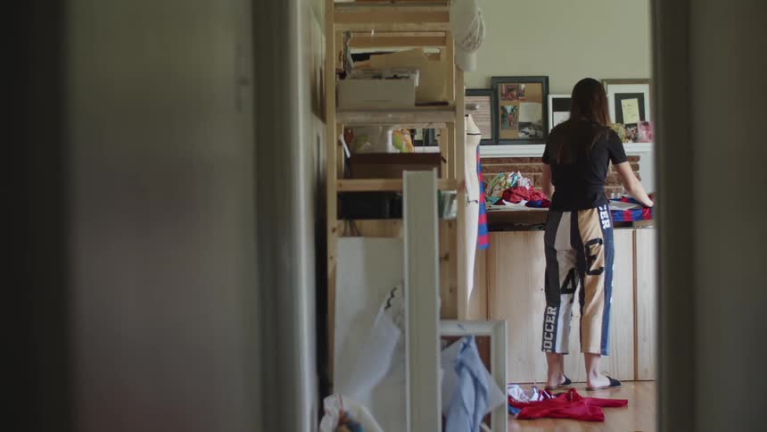 A woman stands at a table and lays out a piece of fabric in a craft room