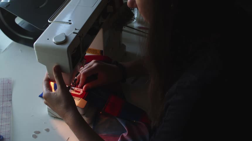 Tailor sewing clothes on a sewing machine in a workshop at home