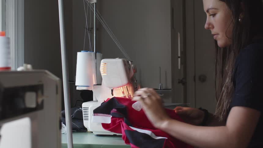 Taylor sewing a shirt in a sewing machine in her home workshop