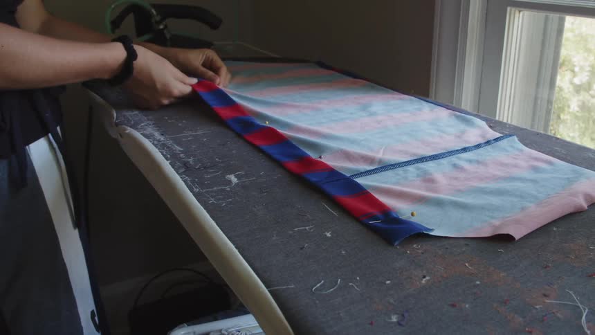 Woman placing pins in a piece of cloth over the ironing table at home