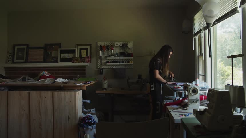 Woman inside of a sewing workshop using an iron on a piece of clothing during the daytime