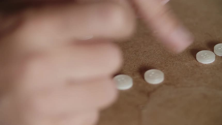 Fingers push white buttons on a brown surface in a counting fashion
