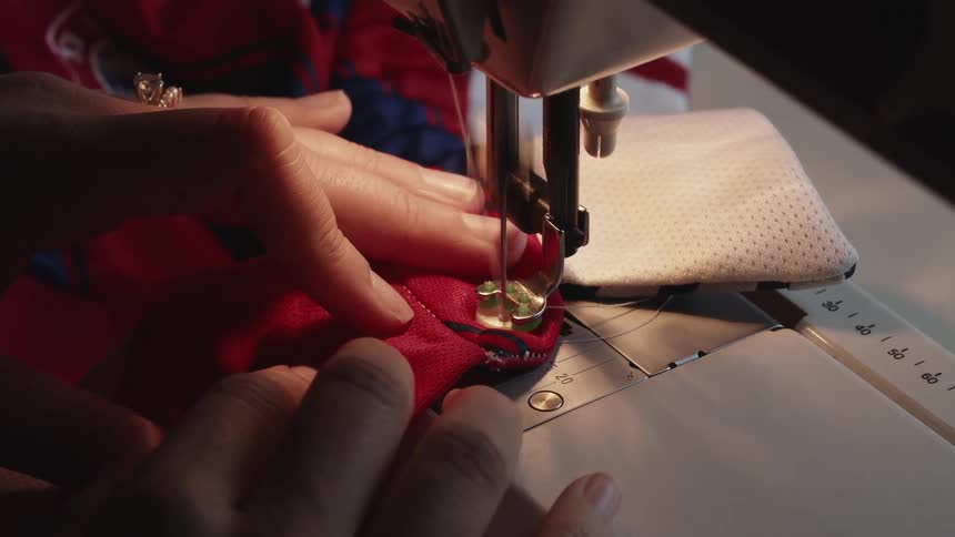 A person sewing a shirt with a sewing machine