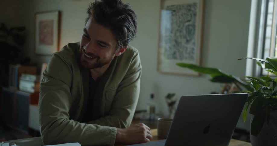 Man with a beard makes a video call on laptop and smiles