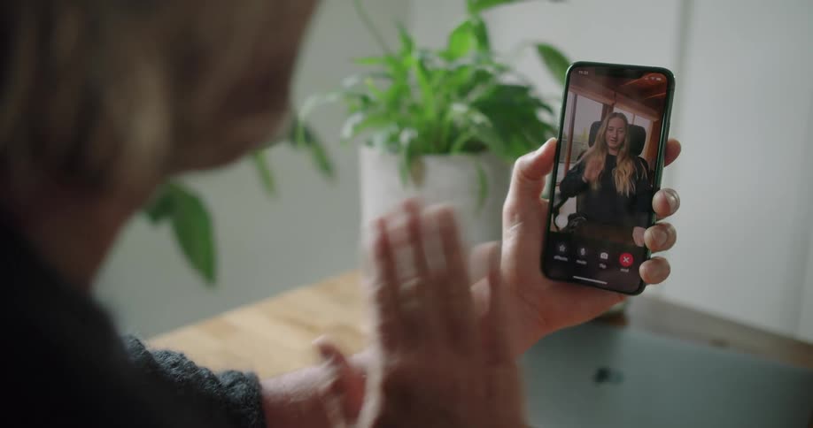 A man waves to a woman on a video call on his cellphone