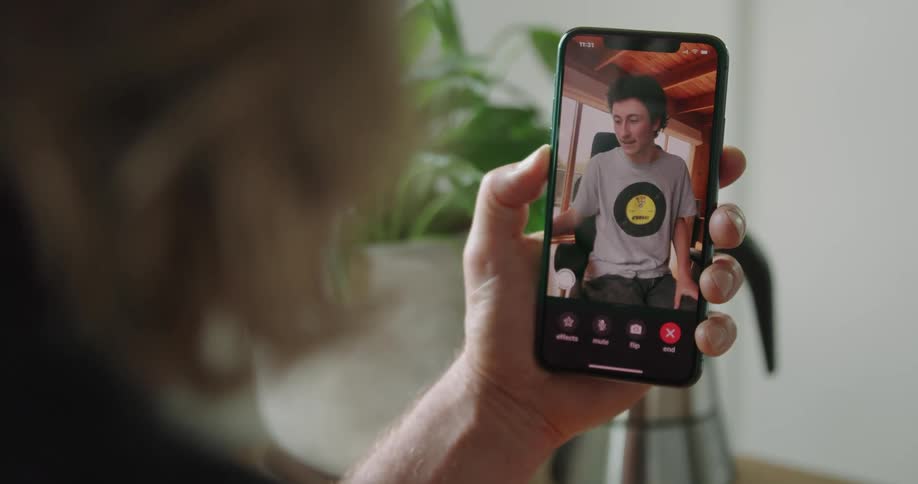 A person holds a cell phone having a video call with another man