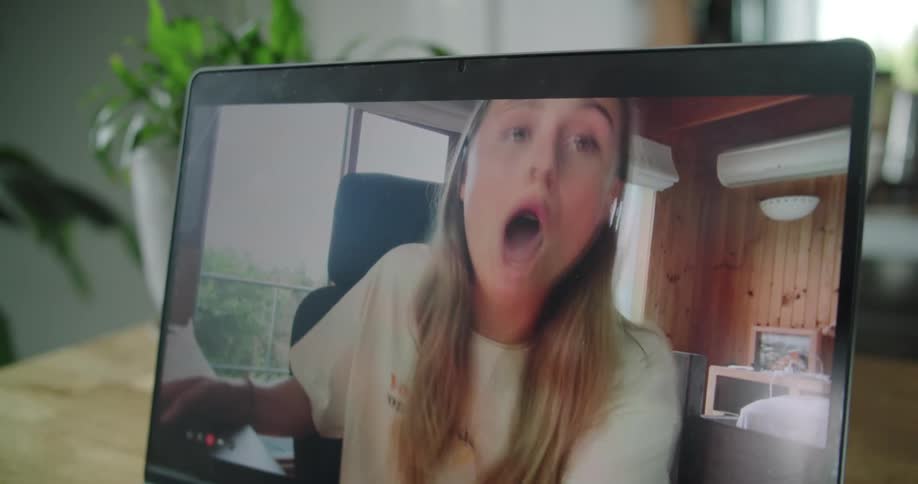 A young woman smiles and kisses toward the camera during a video call