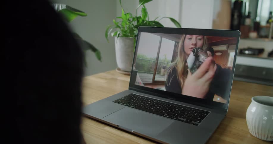 A teenage girl on a laptop screen shows a camera to another person she is video chatting with