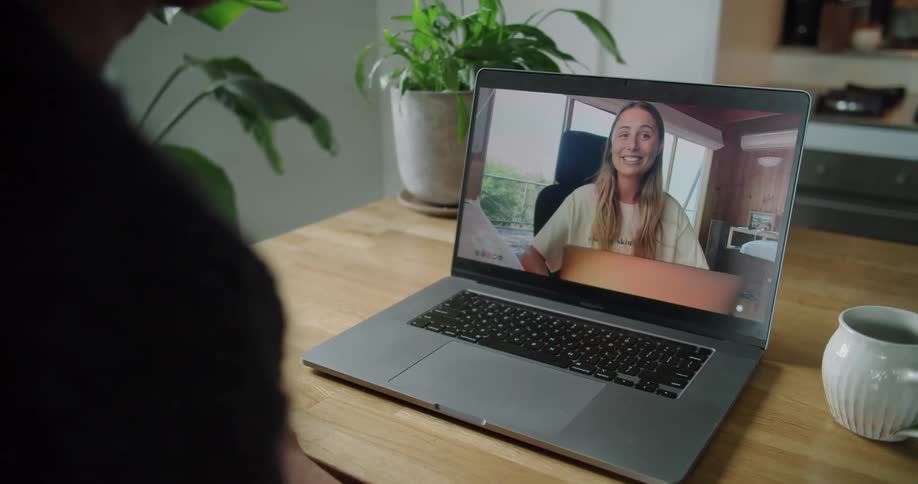 Man sitting at a desk makes a video call with blonde woman on his laptop