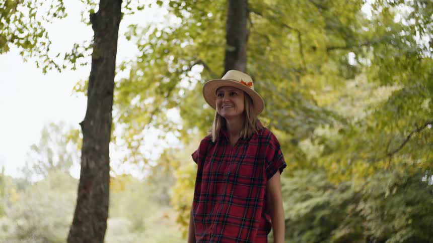 A woman stands in a forest pushing a girl in a swing at daytime