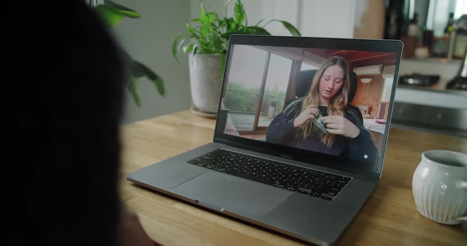 Blonde woman in a video call on a laptop shows a vintage photography camera