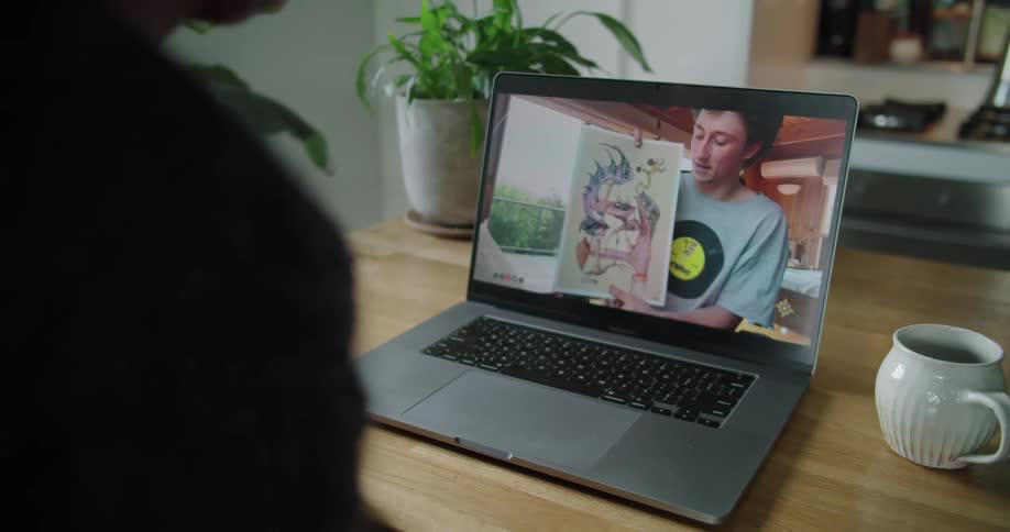 Young man showing a drawing on a video call in a laptop