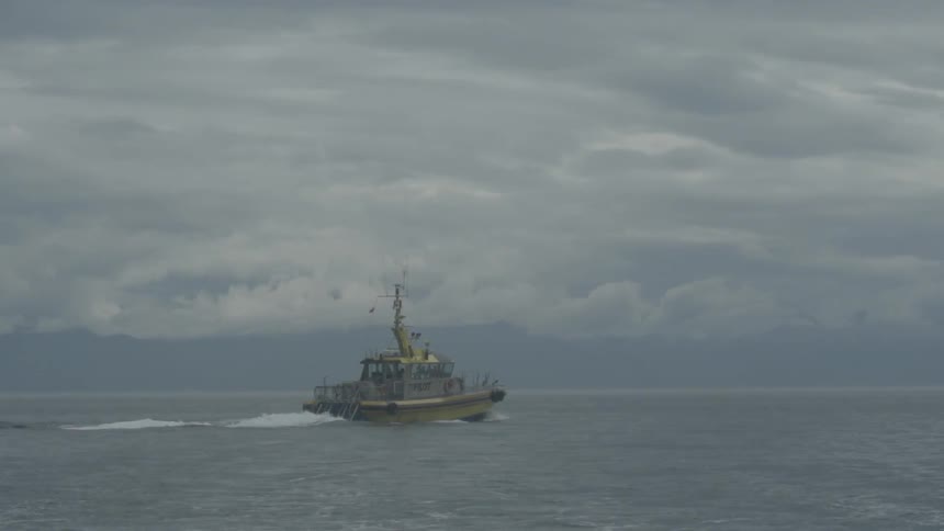 A boat is sailing in the water on a cloudy day