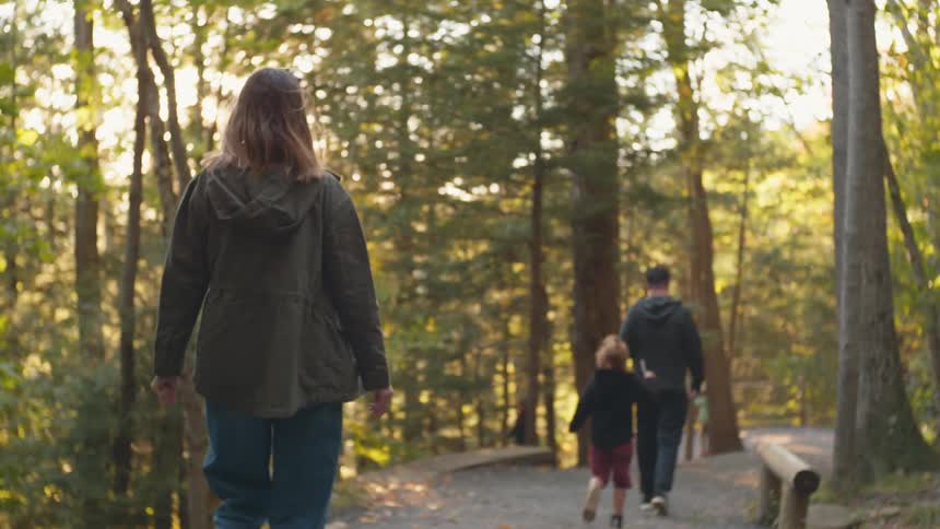 A child running along side her walking parents in the woods