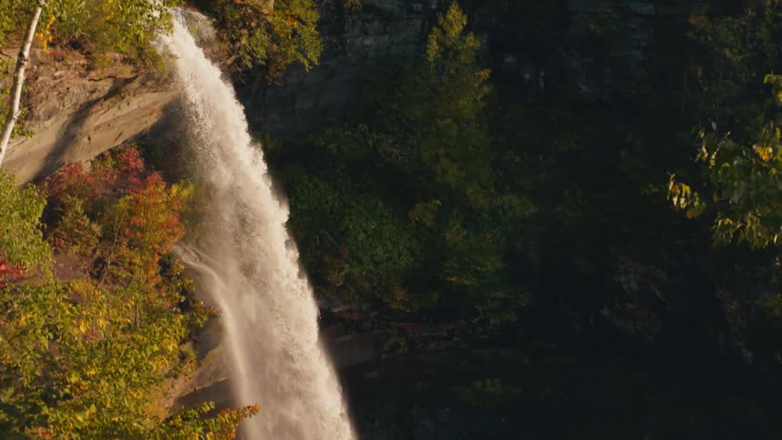 Waterfall falling from a cliff in the mountains at sunset