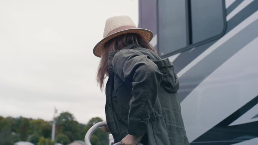 A woman out camping pulls a hose around her trailer