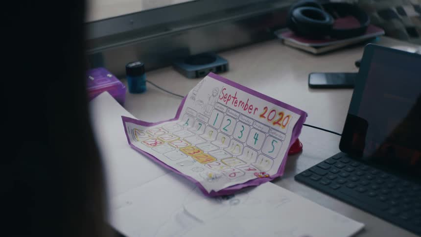 A student looks at a hand drawn calendar next to a tablet laptop computer