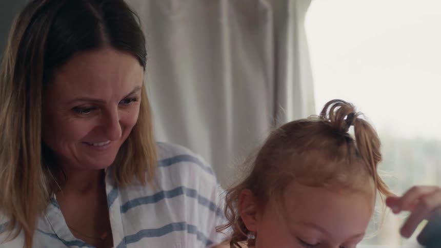 Mother and daughter looking at something in a room at home